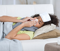 Frau liegt mit Grippe im Bett
